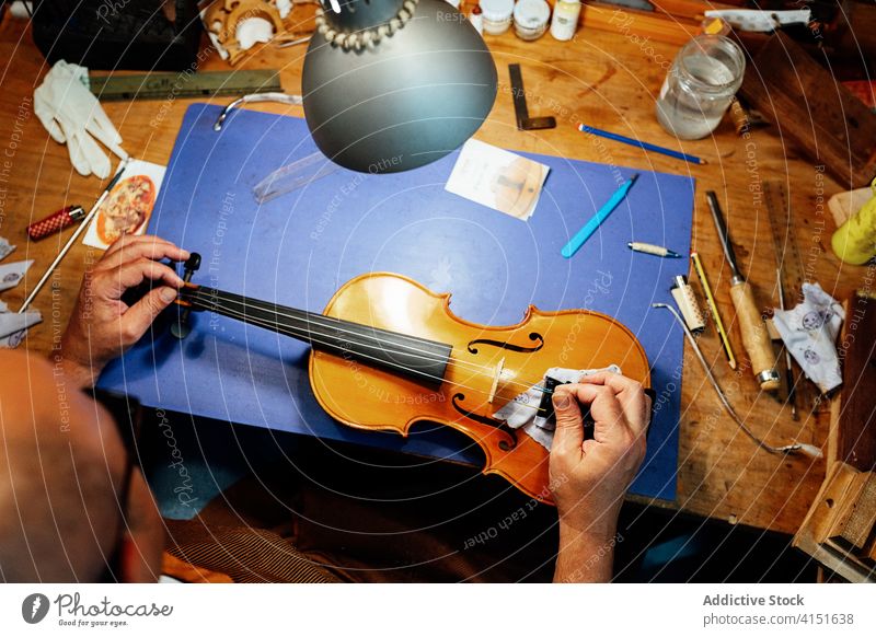 Anonymous craftsman assembling bridge on violin repair string luthier artisan restore work workshop skill master male maker handmade occupation professional fix