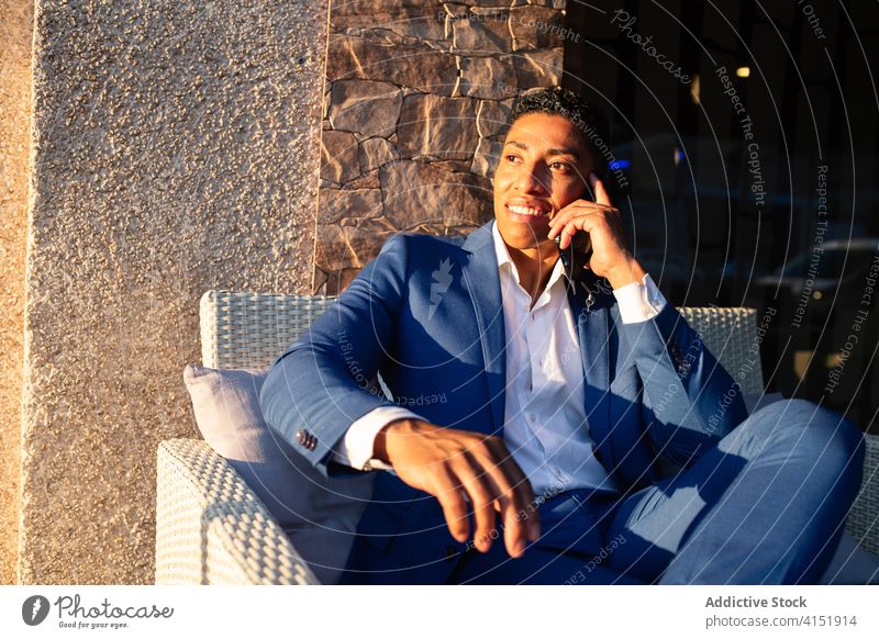 Elegant young businessman talking on smartphone elegant success happy communicate positive formal chair african american black ethnic male leader cheerful
