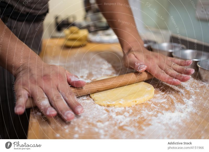 Anonymous person rolling out dough baking at home baker rolling pin team shortcrust kitchen explain cook demonstrate prepare excited ingredient occupation food