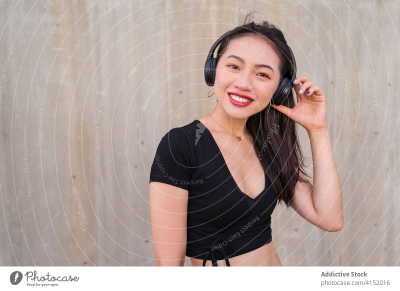 Carefree woman listening to music in headphones carefree smartphone using enjoy female ethnic asian happy cheerful sound modern gadget device young smile lady