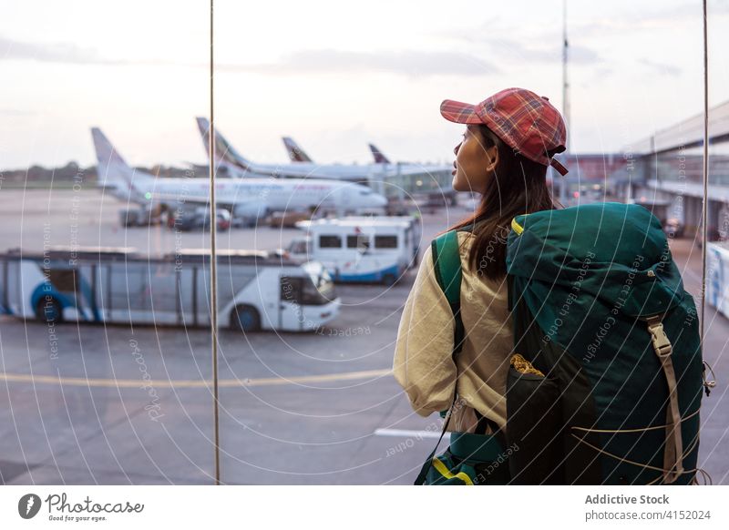 Young woman with backpack standing in airport wait travel window tourism young passenger trip asian ethnic colombo sri lanka flight female traveler journey