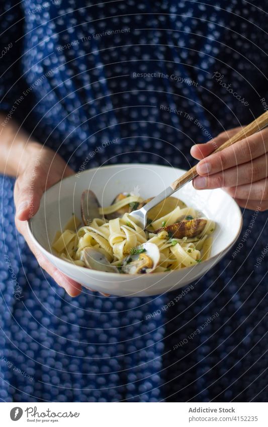 Crop woman eating tasty spaghetti with clams tagliatelle alle vongole dish delicious enjoy bowl tradition female food cuisine mollusc shellfish gourmet meal