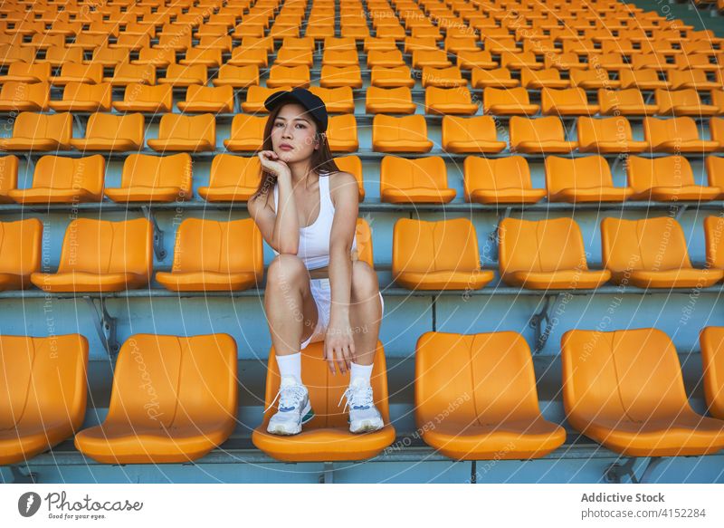 Calm female athlete at stadium woman seat sportswoman relax training workout slender confident asian ethnic fit sit break sporty wellbeing vitality activity