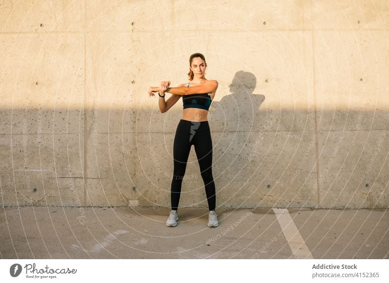 Slim sporty woman stretching body near concrete wall sportswoman exercise fit slim warm up training street active young energy lifestyle fitness athlete