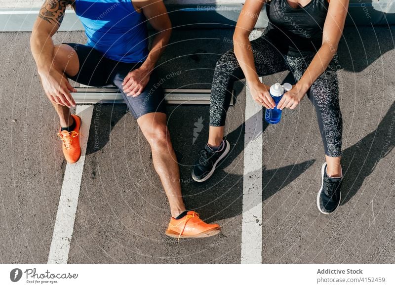 Tired sportive couple relaxing after training tired exhausted sportswoman sportsman sweat workout sportswear street stone wall wellness athlete city together