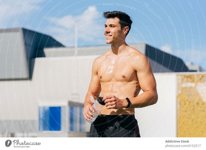 Sweaty sportsman holding water bottle during training smile workout sweat refreshment tired happy sunny rest male athlete terrace drink vitality fit healthy
