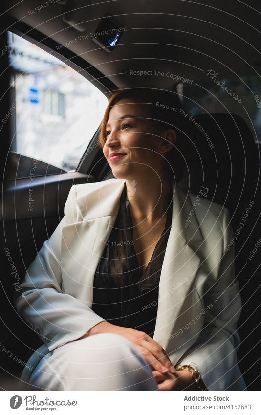 Cheerful female entrepreneur in modern car businesswoman commute work transport taxi suit elegant content executive formal professional passenger seat window