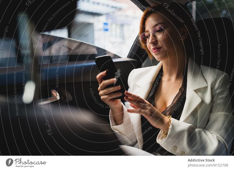 Confident woman with smartphone in car entrepreneur automobile browsing businesswoman work remote check using female elegant costume modern surfing internet