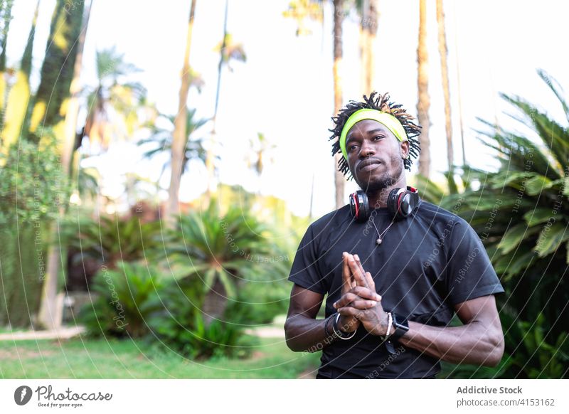 Contemplative ethnic sportsman with clasped hands gesture hands clasped contemplate pray athlete sporty serene park training style young african american black
