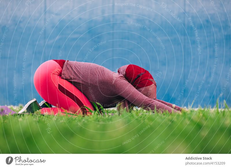 Woman doing yoga in Extended Child pose asana woman practice utthita balasana extended child pose hijab park flexible female ethnic arab meadow green city relax