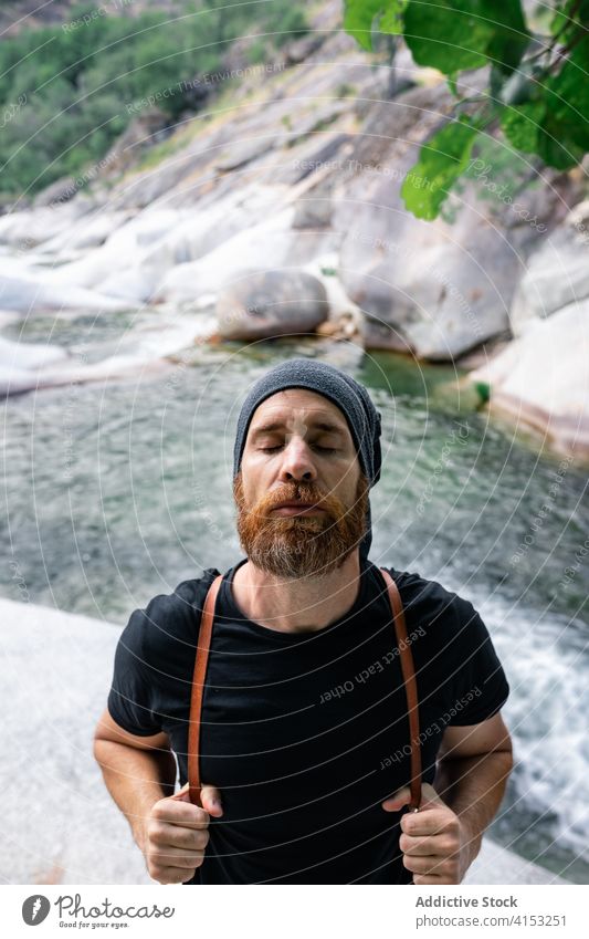 Tranquil traveling man near river in mountains carefree freedom hipster tourism calm harmony nature male traveler rock rapid flow stream relax holiday stone