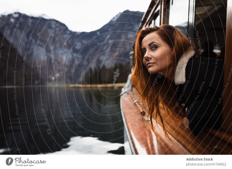 Woman looking out window during boat trip on lake woman travel mountain autumn observe nature journey adventure ship transport young female traveler rock