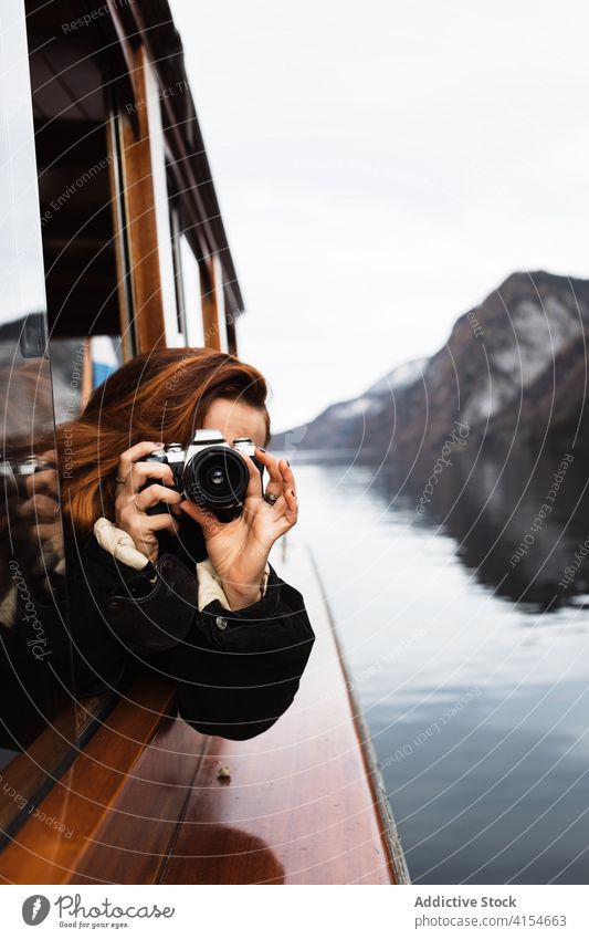 Woman taking pictures from boat during trip on lake woman photo camera travel window photographer take photo autumn nature mountain journey adventure ship