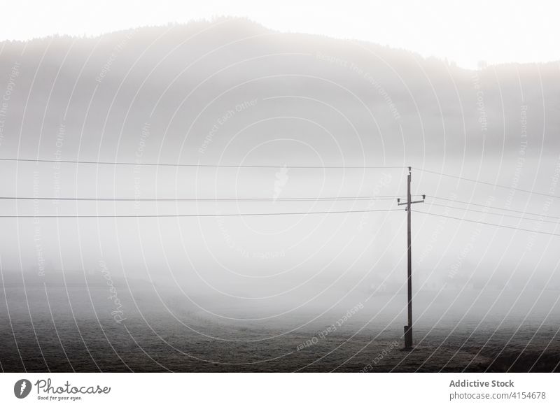 Electric pole and wires in foggy mountain valley cable minimal gray mist morning landscape electric cold nature scenery environment haze weather range season