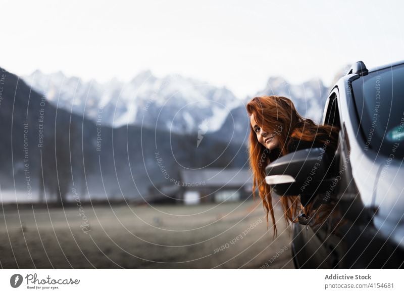 Woman looking out window during road trip in mountainous terrain woman travel car autumn observe nature journey adventure countryside vehicle destination route