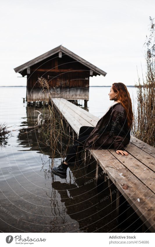 Lonely woman standing on wooden pier at lake shed autumn gloomy lonely traveler shabby calm tranquil nature female tourism germany austria water gray cloudy