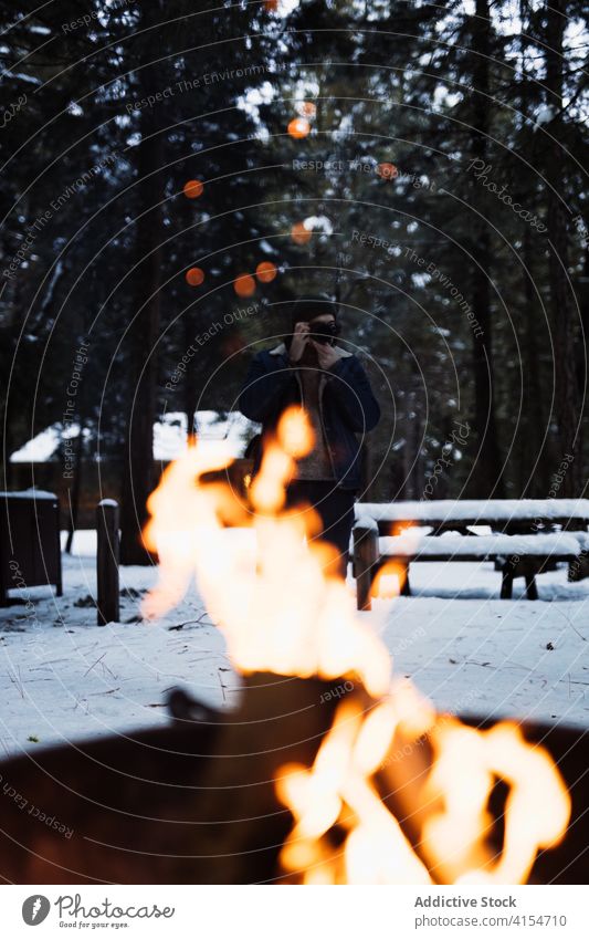 Traveler taking photo of campfire in winter forest bonfire take photo traveler photographer flame snow fireplace cold season adventure nature woods wanderlust