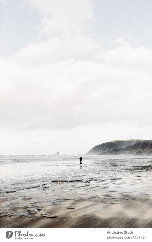 Person at seaside on cloudy day seashore person walk seascape gloomy overcast foam nature usa united states america weather sky ocean calm daytime destination