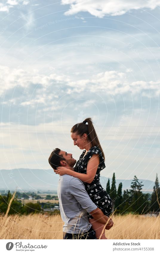 Delighted couple in field in summer lift love together relationship in love hug meadow girlfriend boyfriend happy romantic relax affection date cheerful rest