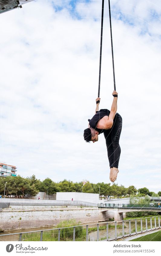 Flexible man training on aerial straps gymnast gymnastic hang perform flexible fit park male workout exercise energy athlete sport healthy sportswear effort