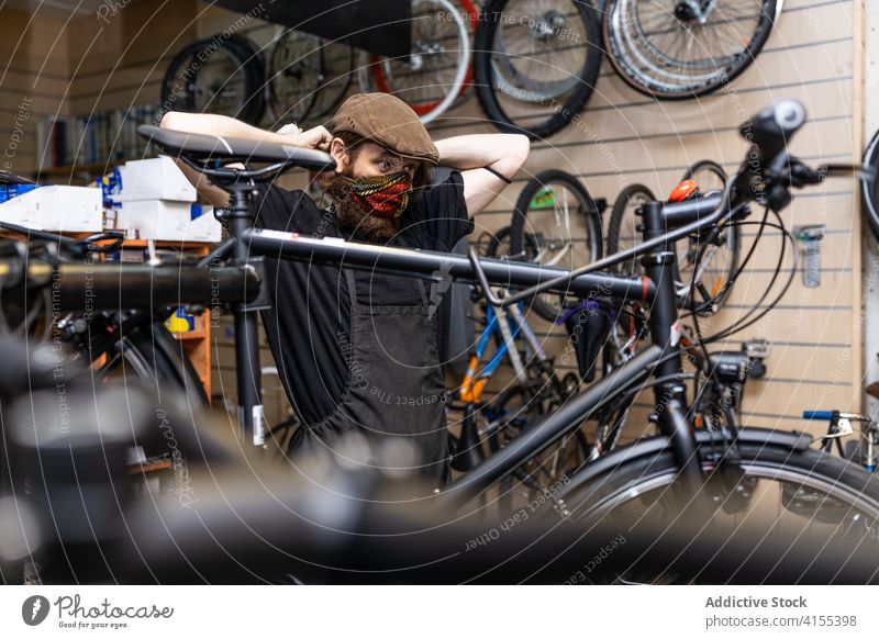 Mechanic putting on protective mask in workshop man bicycle covid put on repair mechanic bike maintenance occupation service male professional repairman