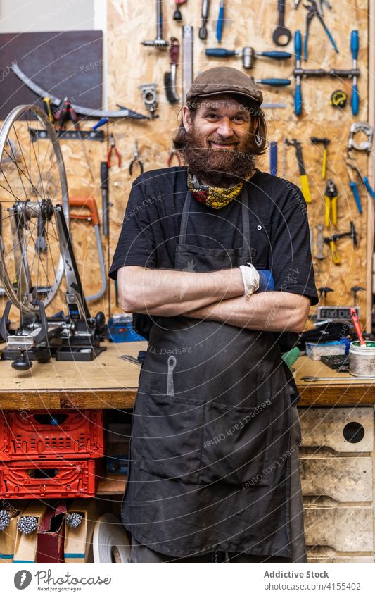 Positive mature handyman in workshop repairman craftsman mechanic beard positive portrait occupation confident friendly smile bicycle owner maintenance service