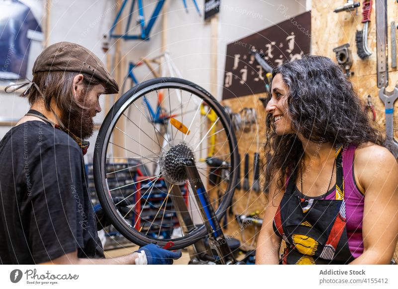 Couple of mechanics working in bicycle service together couple workshop owner small business fix repair bike wheel cheerful happy occupation labor lifestyle