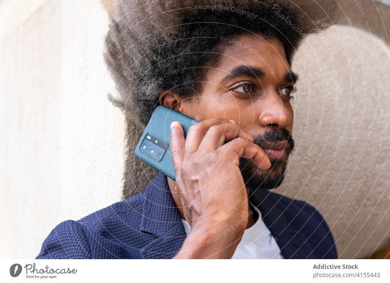 African man using his mobile phone black ethnic afro american suit business businessman barcelona street outdoors traveler device cellphone smartphone