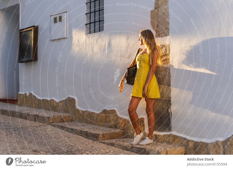 Content woman in dress near building city tourist summer sunlight vacation historic town sunny female wall stone travel street delight holiday enjoy smile happy