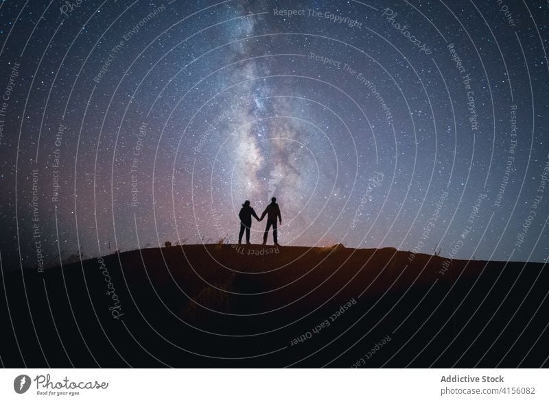 Anonymous loving couple on hill in highlands travel mountain milky way admire enjoy holding hands stand relationship traveler tender journey romantic tourism