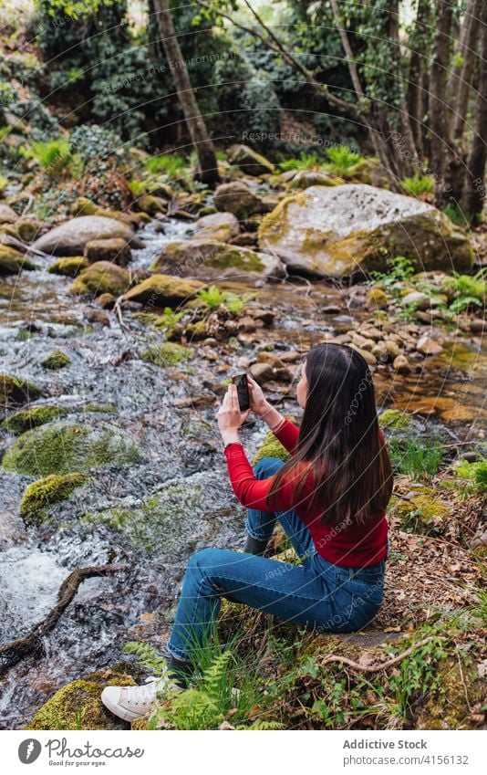Traveling woman taking photo on smartphone in forest take photo traveler enjoy river woods memory nature female valle del jerte caceres spain tourist shore sit
