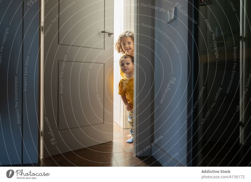 Cute siblings in doorway at home peep children playful brother sister having fun little apartment together cheerful modern cute adorable joy happy cozy smile