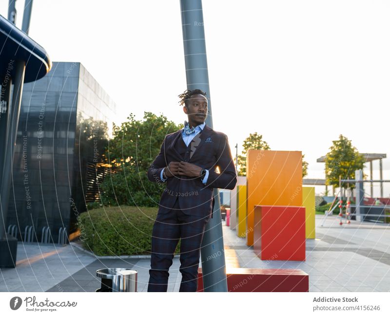 Confident businessman in stylish suit in city classy entrepreneur determine leaning serious streetlight sunlight downtown metropolis male ethnic black