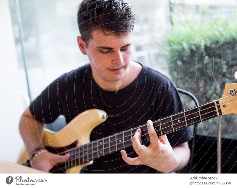 Young man playing bass guitar music accord skill perform musician instrument sound melody song hobby young male learn lifestyle guitarist practice talent string