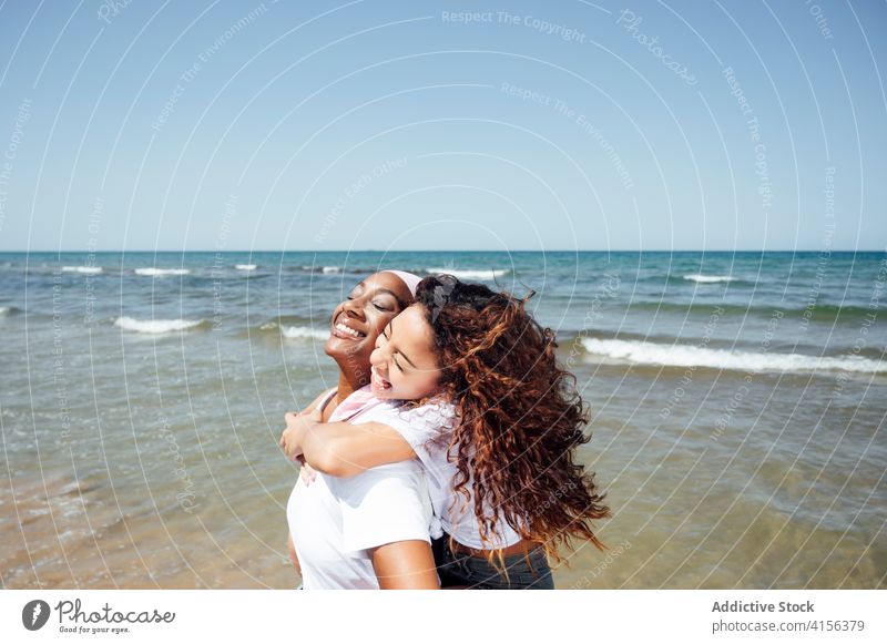 Cheerful mother piggybacking daughter on beach ride having fun bonding relationship cheerful together ethnic black african american happy seaside summer smile