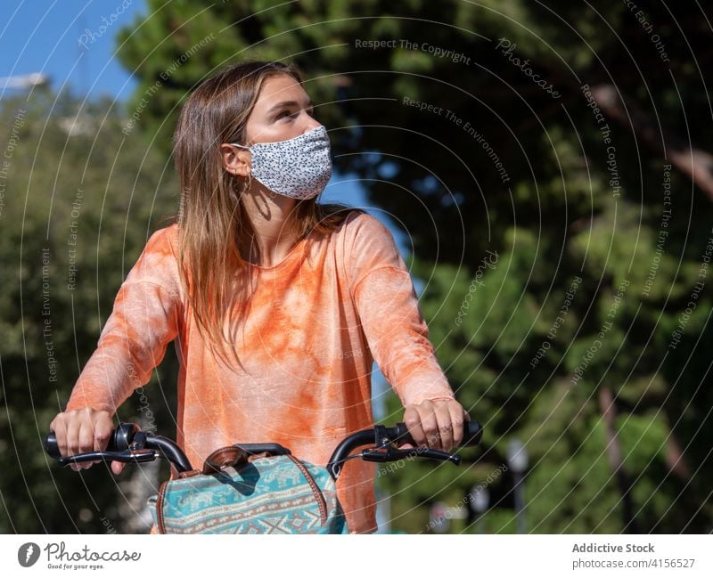 Young woman in mask riding bicycle ride street commute pandemic young casual summer female bag coronavirus covid19 covid 19 new normal student madrid spain bike