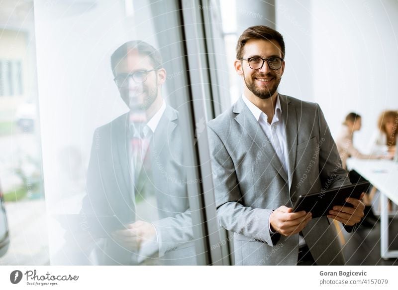 Young modern businessman using digital tablet in the office beard company corporate employee eyeglasses financial handsome indoors job leadership male manager