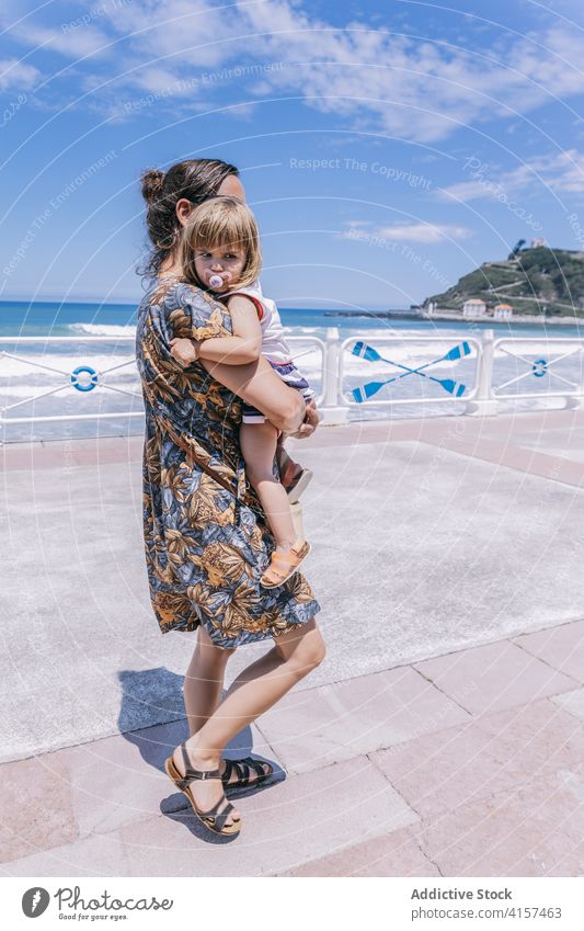 Woman with little girl on embankment in summer mother daughter sea vacation seafront promenade sunny together cute happy kid mom relax childhood parent charming