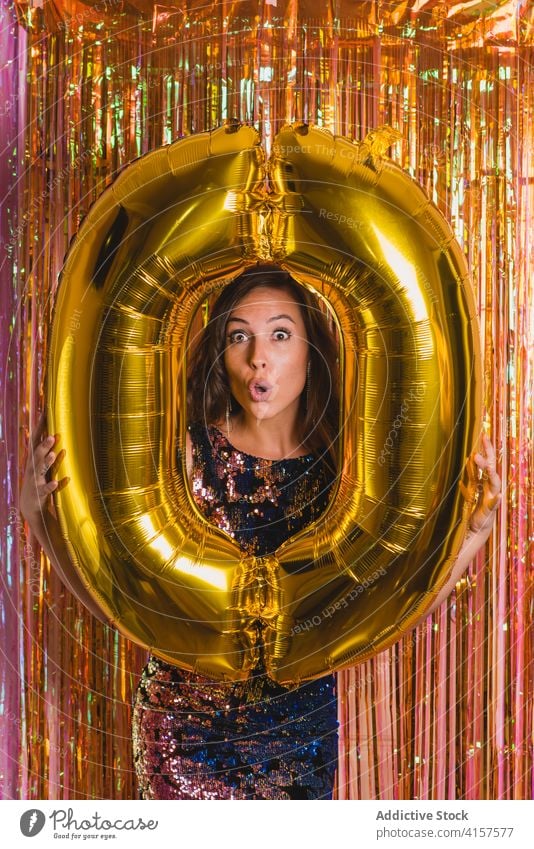 Cheerful woman with golden balloon during New Year party new year 0 number celebrate festive happy holiday young female cheerful event fun shiny vibrant vivid