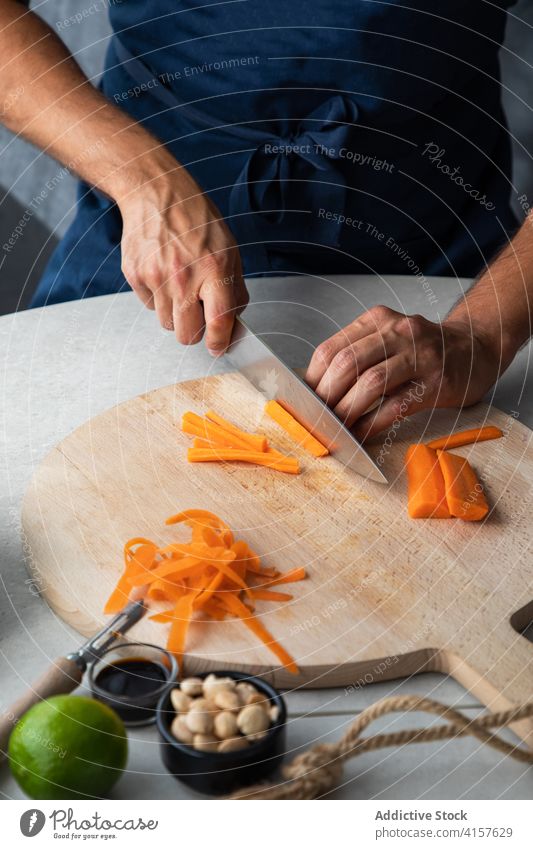 Cook cutting carrot on wooden board cook chop vegetable food prepare fresh kitchen culinary ingredient healthy knife cuisine meal organic vegetarian