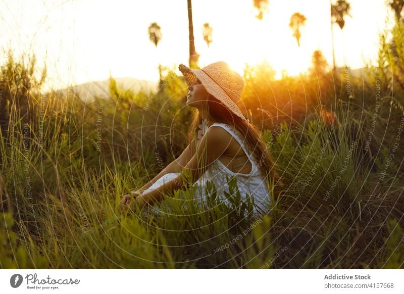 Charming woman in field in summer sunhat meadow sunset evening tender carefree relax female smile nature enjoy cheerful romantic rest sundown peaceful grass