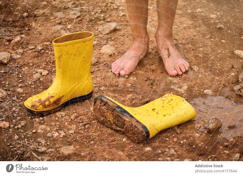 Dirty muddy bare feet with a pair of water boots on a muddy path schoolboy lifestyles messy weekend problem rain skin wet weather earth playing drop kid outside