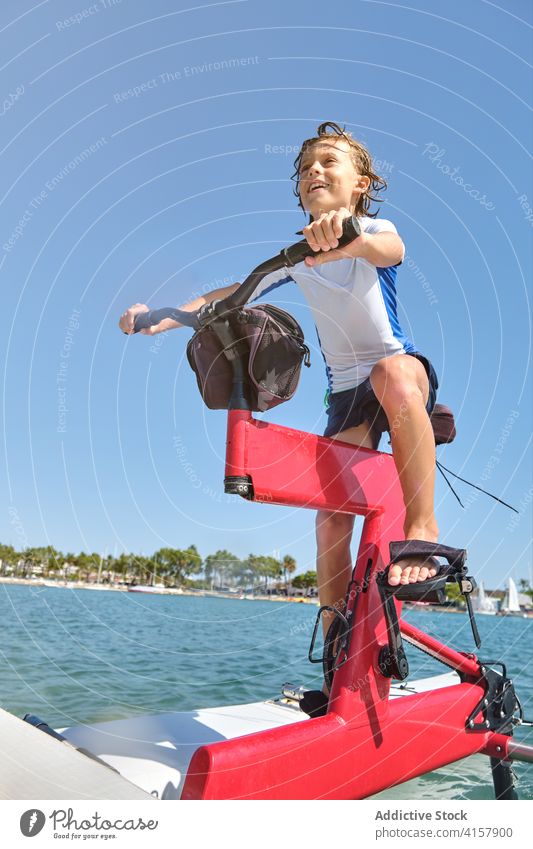 Boy riding on a water bike with happiness expression lifestyles ride wellness gesture challenge balance satisfaction men palm tranquility recreation drive joy