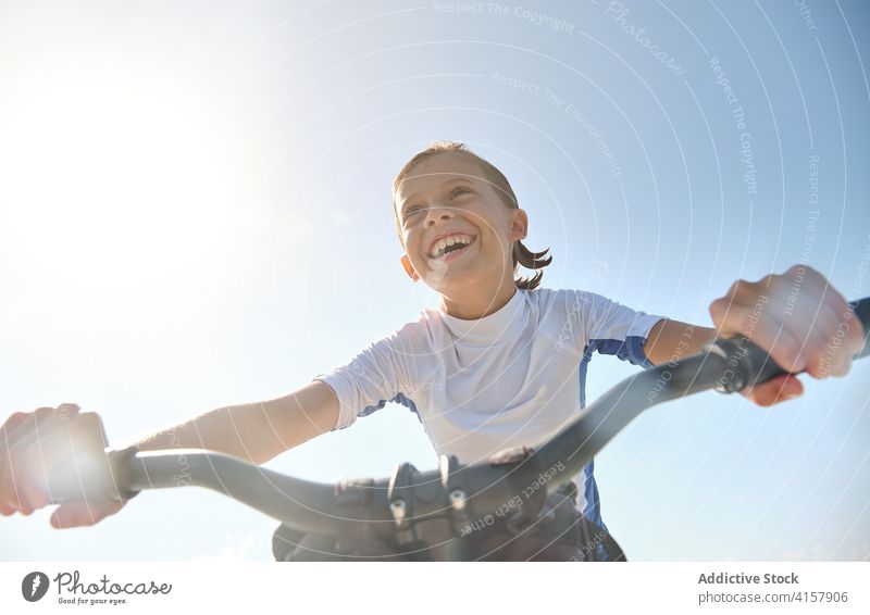 Vertical photo kid smiling and pedaling on a water bike sunbeam wellness challenge tranquility lifestyles ride gesture balance men palm recreation drive joy