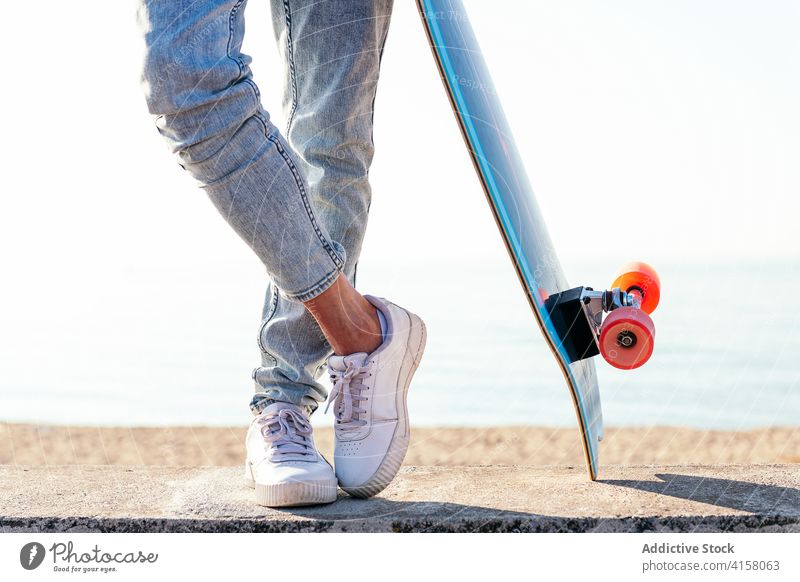 Crop skater on modern skateboard in city sneakers feet street summer style youngster cool jeans urban contemporary active activity outfit hipster trendy hobby