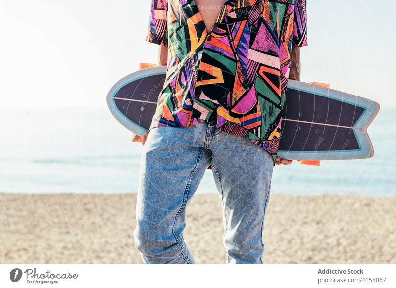Stylish man with skateboard standing on seafront skater faceless hipster lifestyle trendy close up crop view activity summer young male modern millennial funky