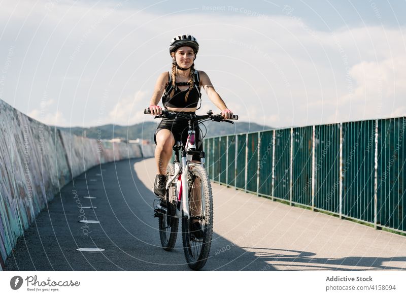 Active woman riding bicycle on paved road ride cyclist activity bike sporty path exercise young female helmet lifestyle way enjoy confident summer trip