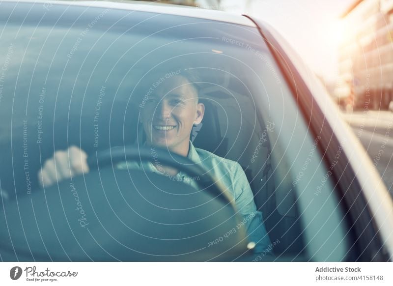Smiling man driving car in city driver ride road roadside route way smile male handsome masculine roadway auto automobile automotive vehicle transport modern