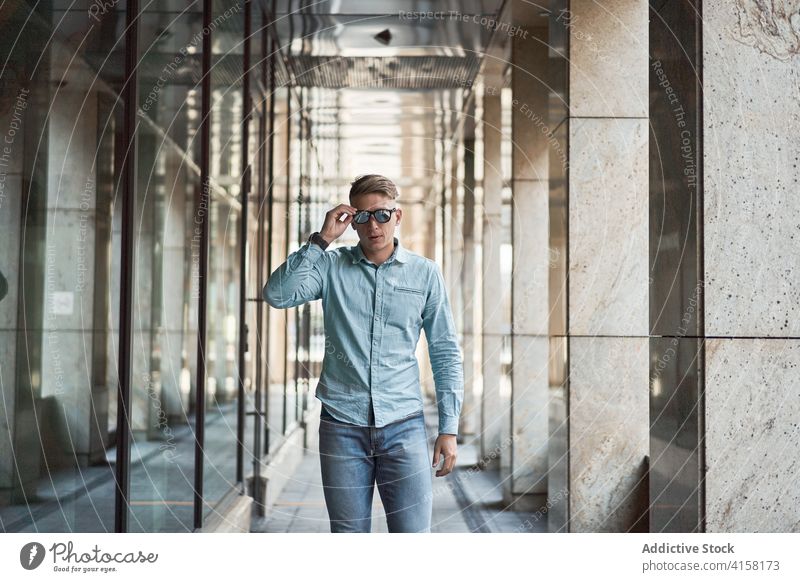 Stylish man in sunglasses in city smart casual style trendy confident emotionless handsome building male modern outfit serious urban contemporary young fashion