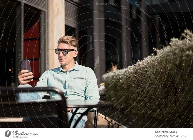 Content businessman browsing smartphone in cafe in summer remote work entrepreneur masculine handsome using male gadget device surfing mobile freelance